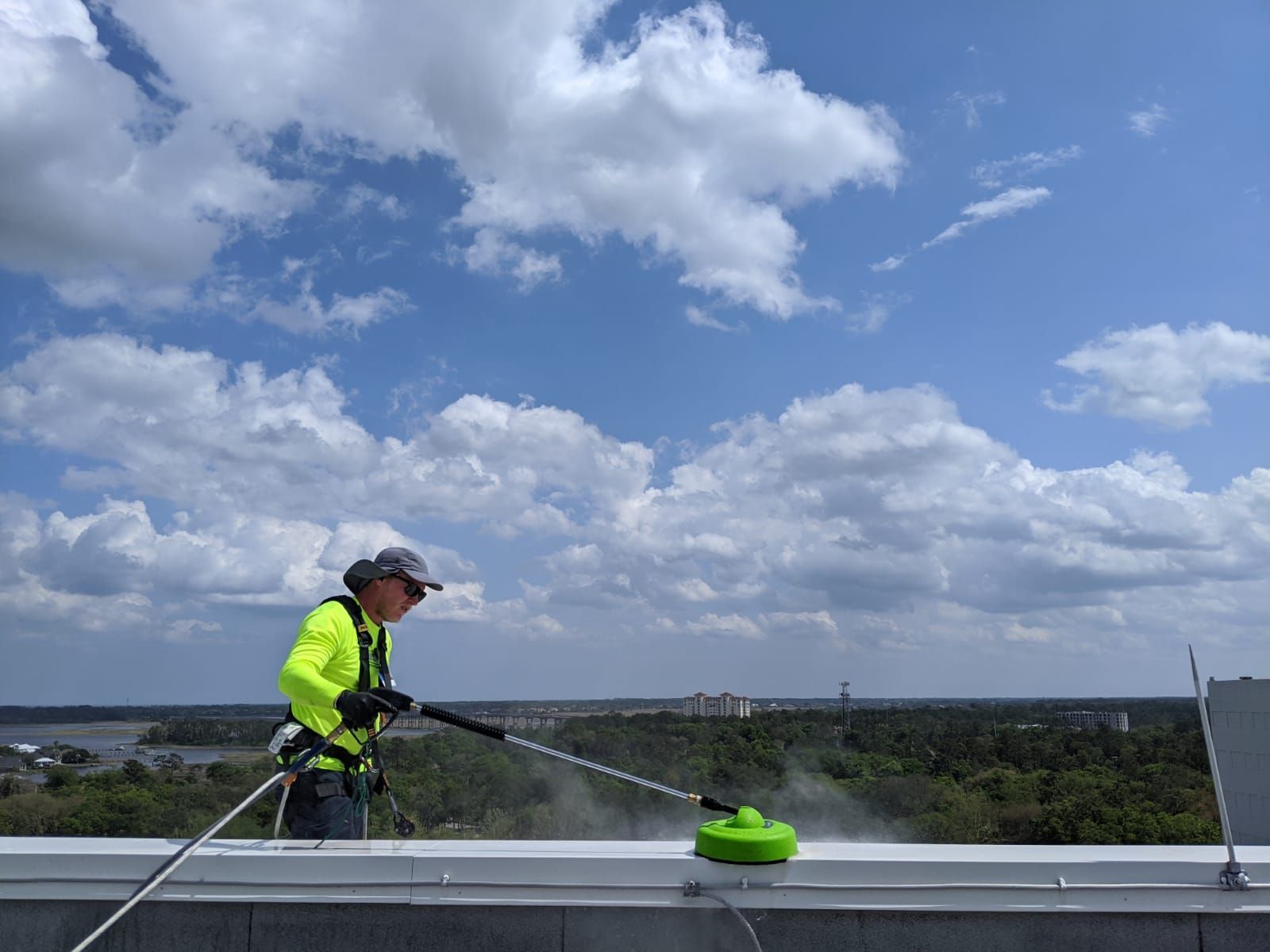 Technician using a surface cleaner on a rooftop parapet with the Intracoastal behind